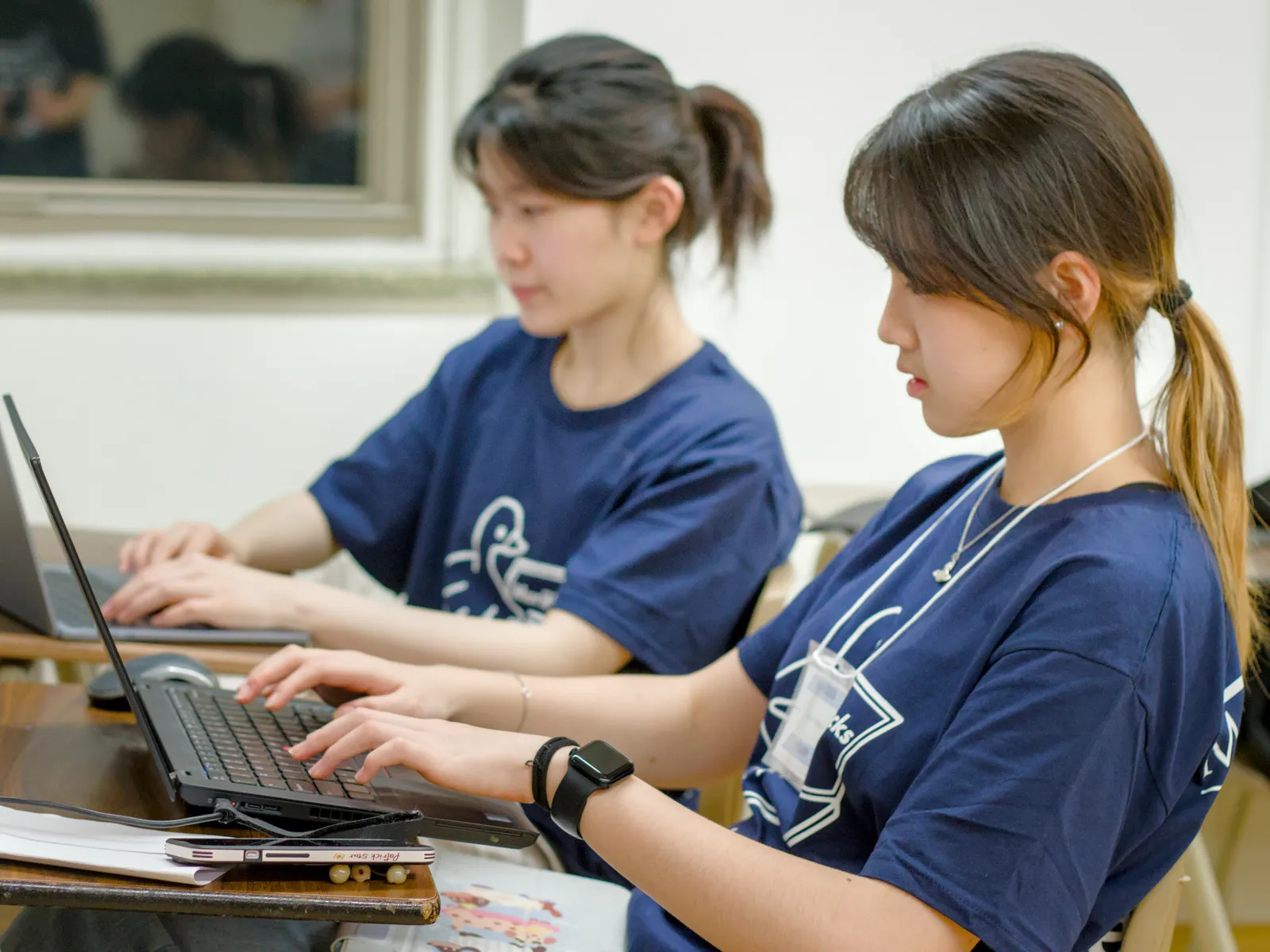 Two MariHacks organizers working side by side on laptops.